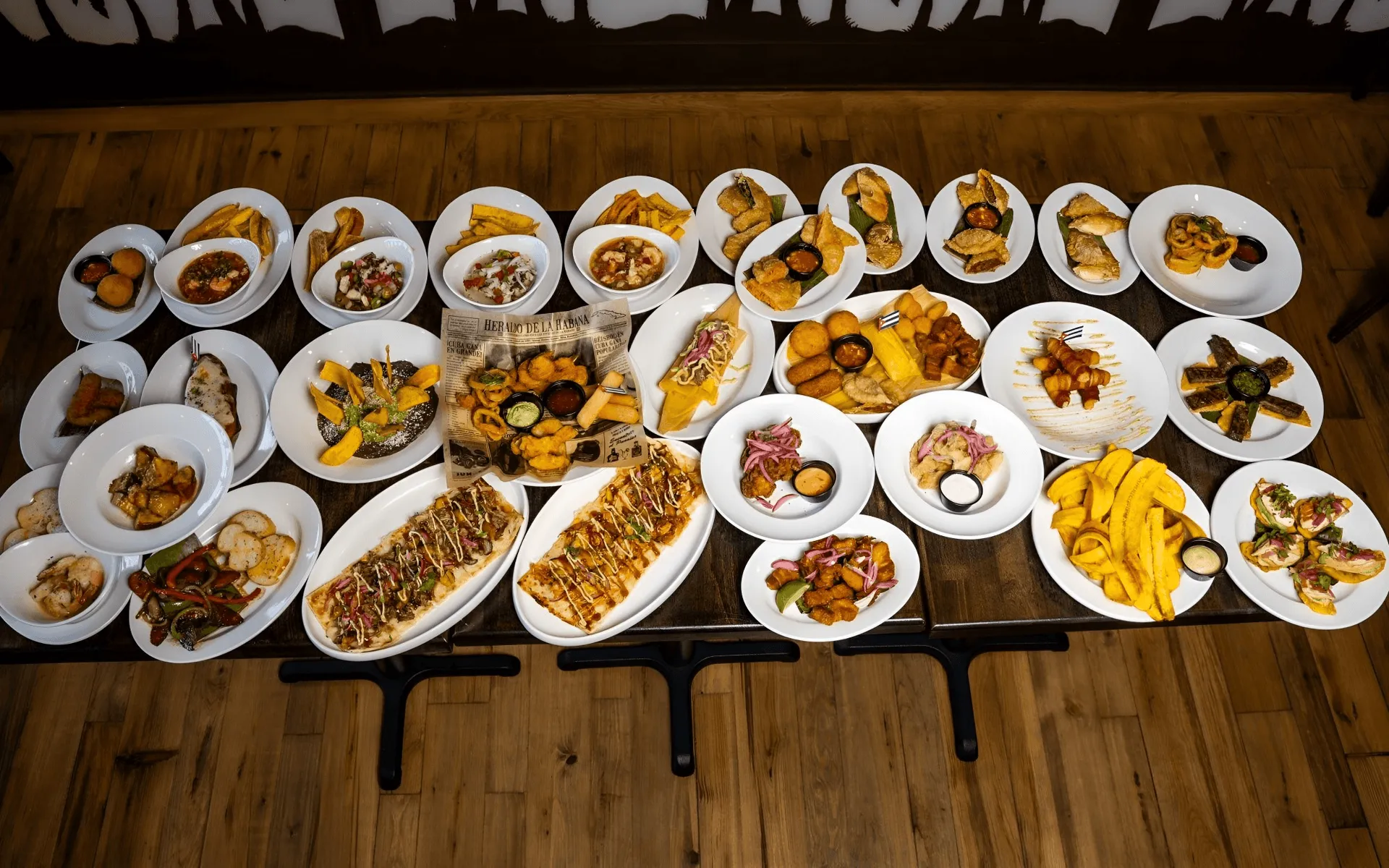 Overhead view of a full table of Cuban appetizers, croquetas, empanadas, tostones and flatbreads