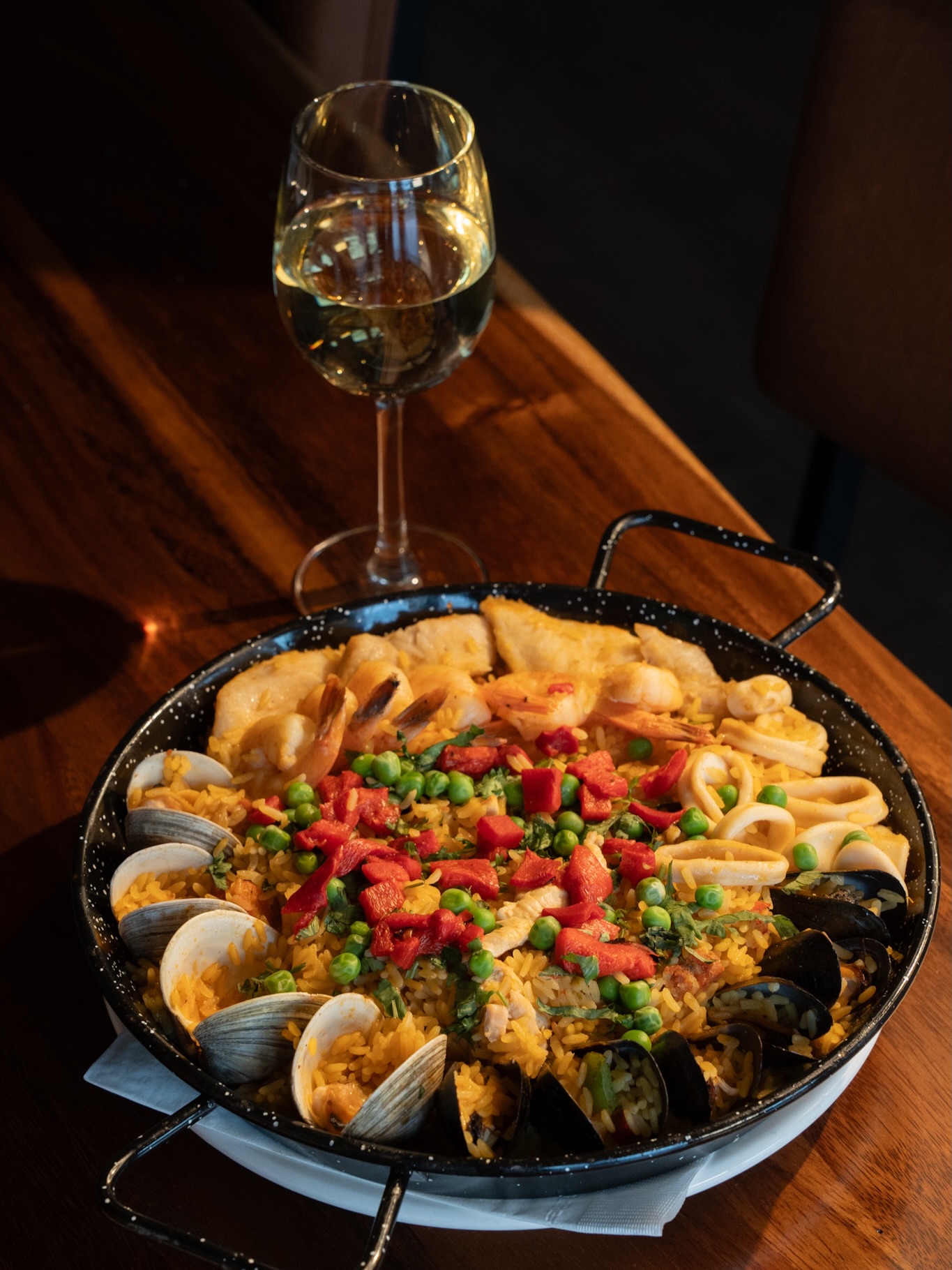 Mambo seafood paella with shrimp, clams, mussels, and a glass of wine